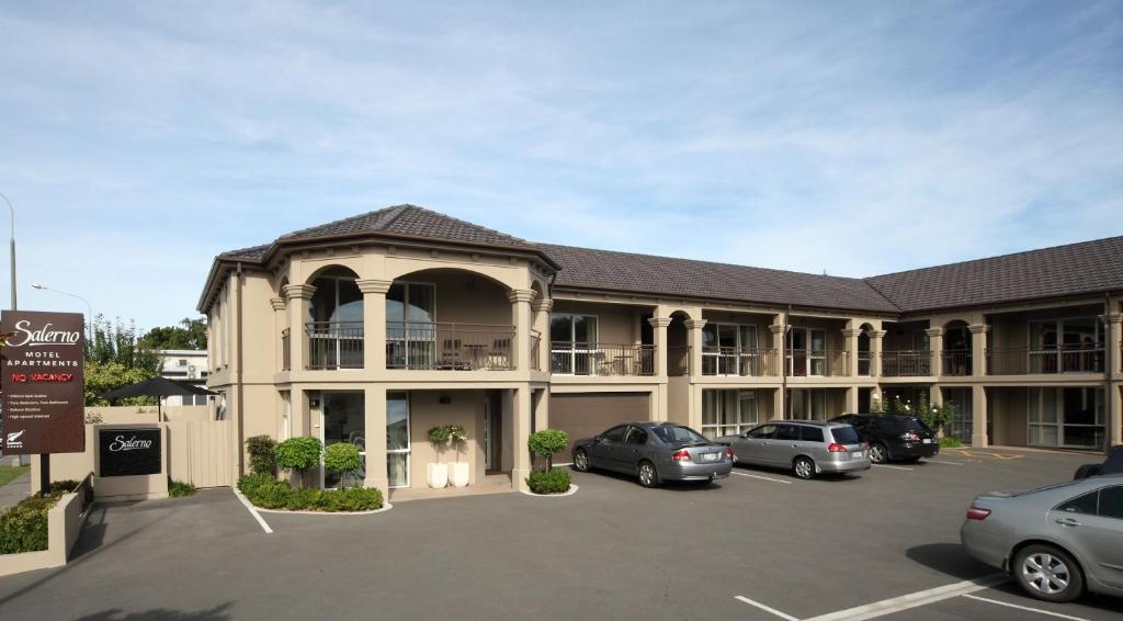 un grand bâtiment avec des voitures garées dans un parking dans l'établissement Salerno Motel Apartments, à Christchurch