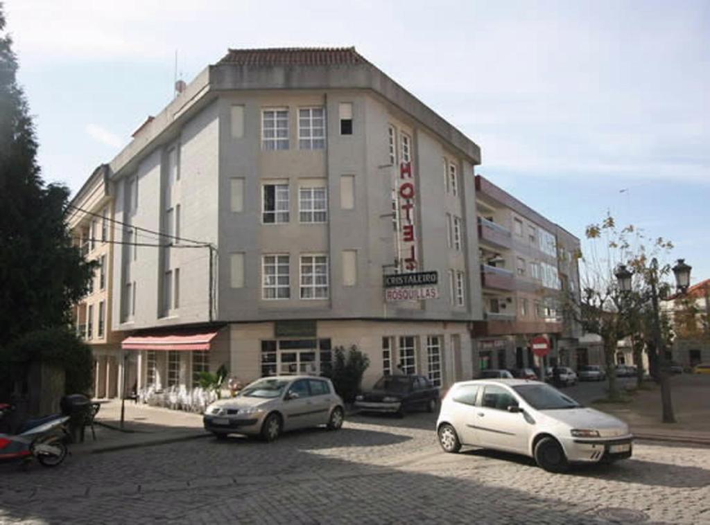 zwei Autos auf einem Parkplatz vor einem Gebäude geparkt in der Unterkunft Hotel Cristaleiro in Gondomar