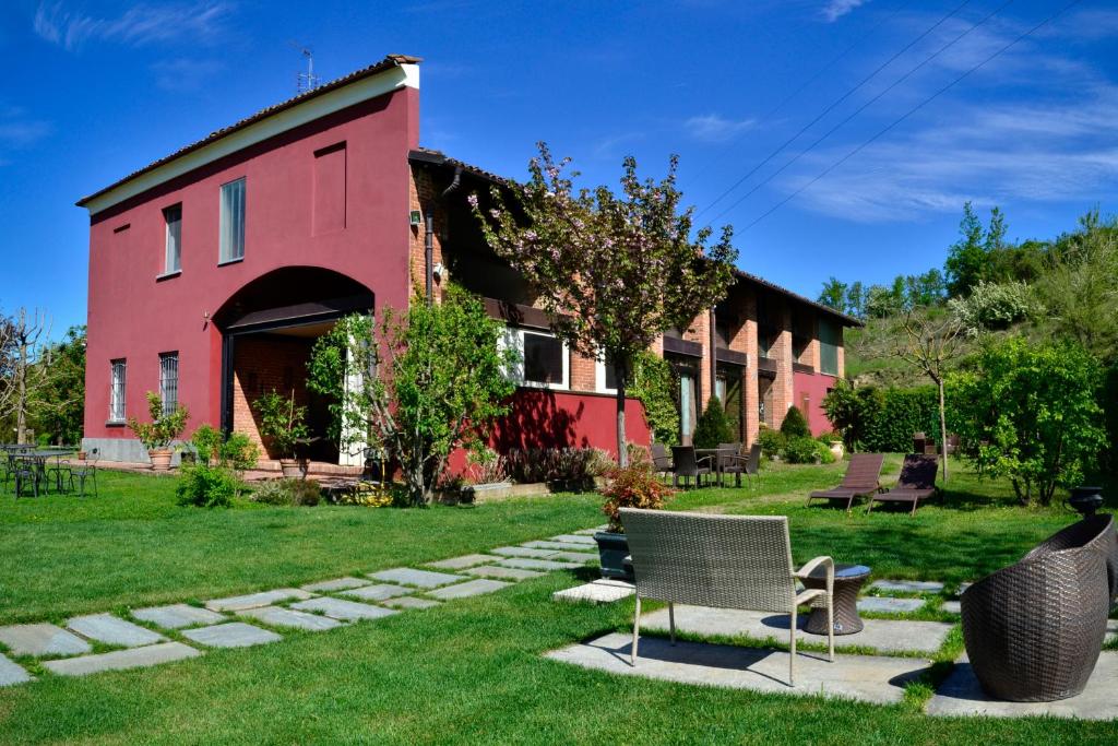 um edifício vermelho com cadeiras na relva em Agriturismo Tenuta Polledro em Asti