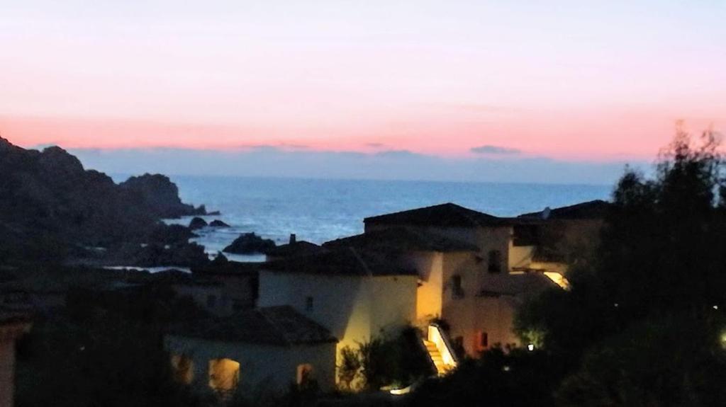 una vista de una ciudad por la noche con el océano en Bouganville Residence, en Isola Rossa