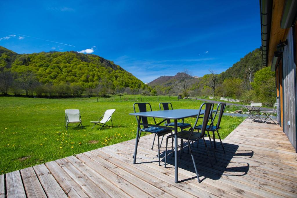 einen Tisch und Stühle auf einer Terrasse mit Blick auf ein Feld in der Unterkunft La Dormeuse du Val in Chambon-sur-Lac