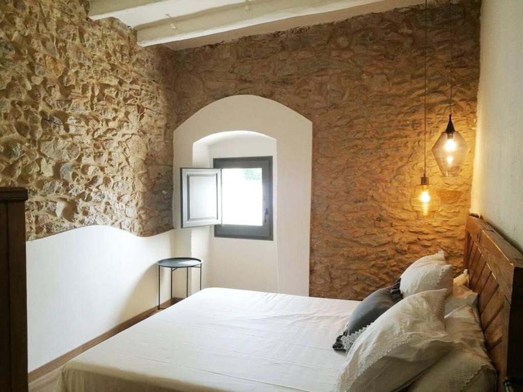 a bedroom with a large bed in a stone wall at Can Puig de la Pera in La Pera
