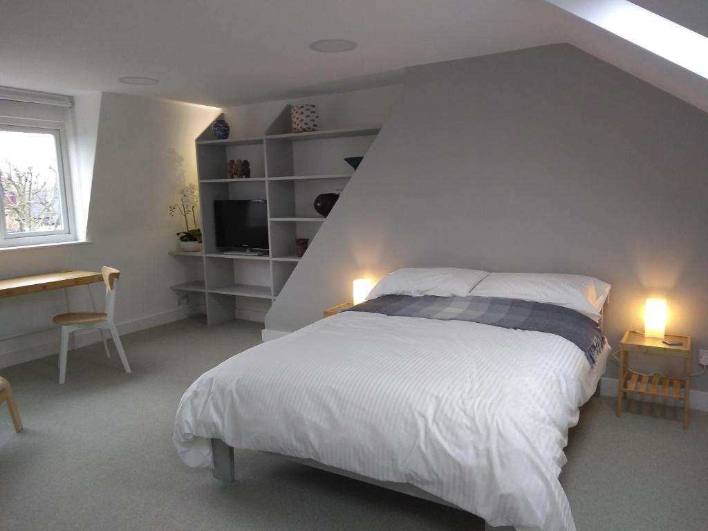 a bedroom with a bed and a desk and a window at Sandra & Andrew's B&B in London