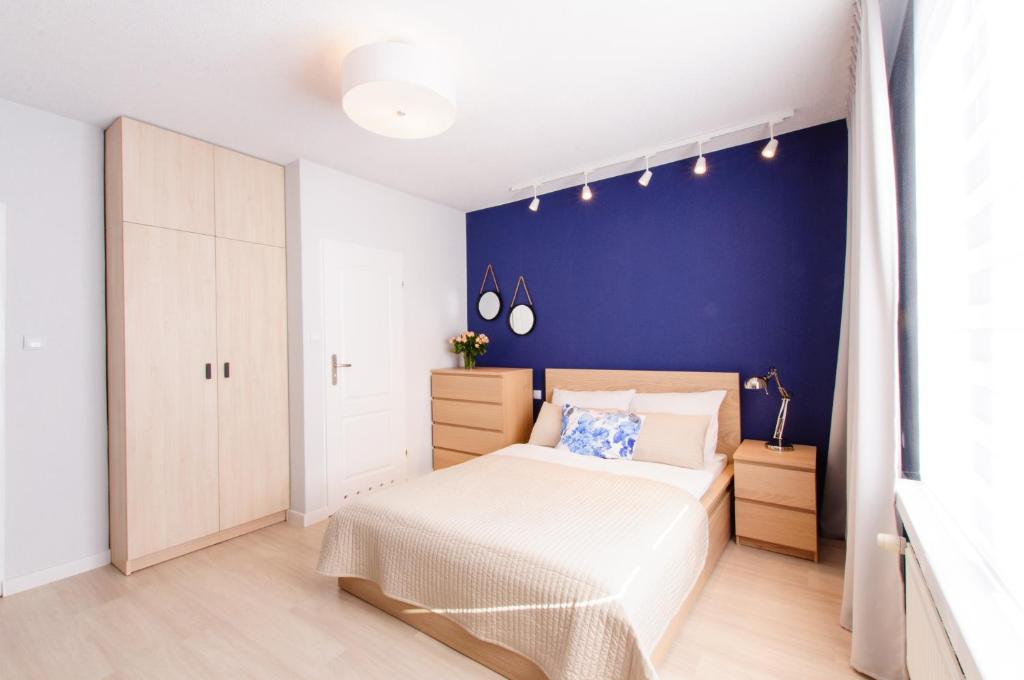 a bedroom with a bed and a blue wall at Pokoje Gościnne Abelard in Ustronie Morskie
