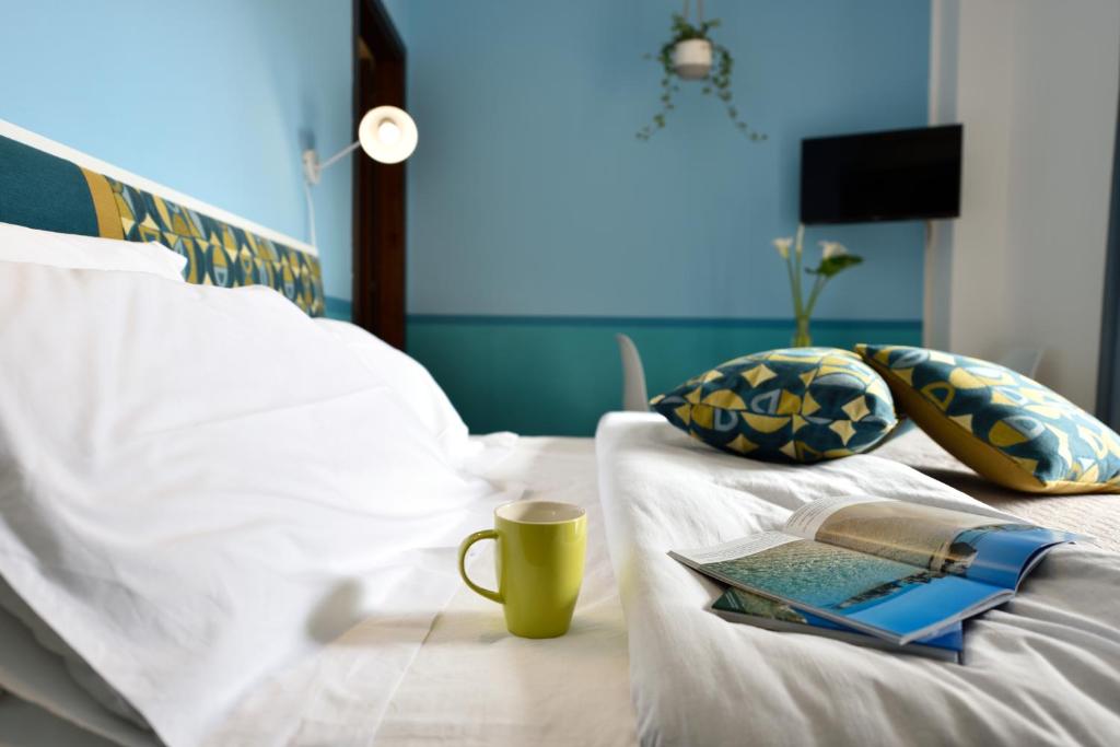 a bed with a laptop and a cup on it at La Tortorella Room & Apartment in Tortolì