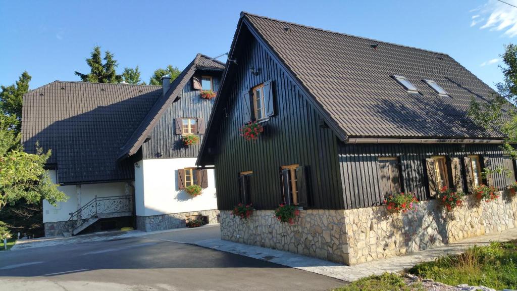 a black and white house with potted plants at Pansion House Prijeboj in Jezerce