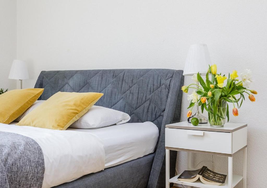 uma cama com almofadas amarelas e uma mesa com um vaso de flores em Rent a Home Delsbergerallee - Self Check-In em Basileia