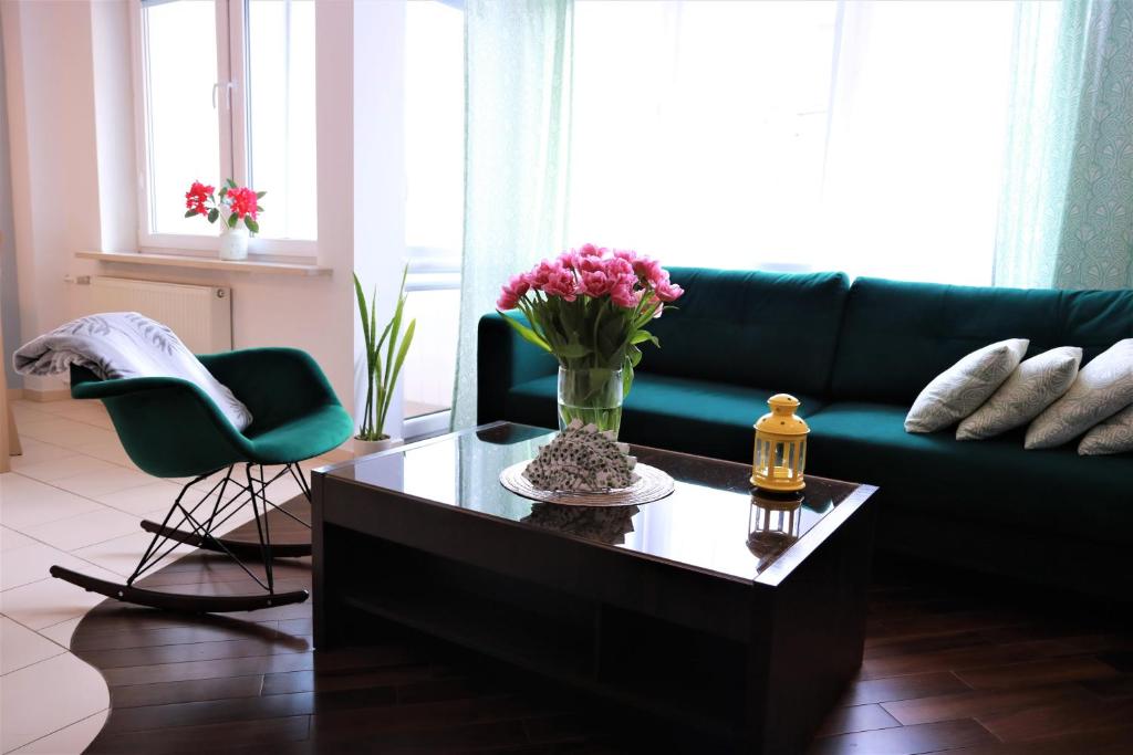 ワルシャワにあるStylish and spacious by Cooee Apartmentsのリビングルーム(ソファ、花のテーブル付)