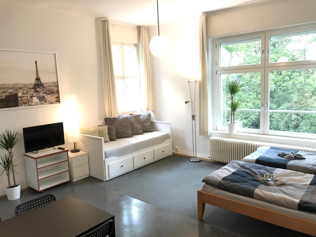 a living room with a couch and a bed and windows at Ferienwohnungen und Apartmenthaus Halle Saale - Villa Mathilda in Halle an der Saale