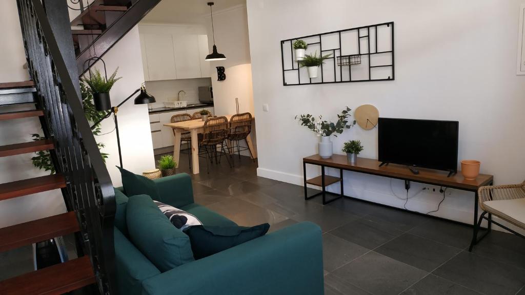 a living room with a blue couch and a television at Bartholomeu GuestHouse 2 in São Bartolomeu de Messines