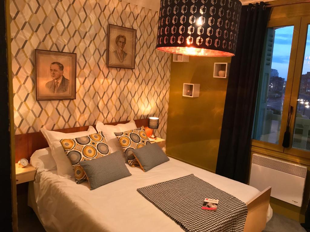 een slaapkamer met een bed met kussens en een lamp bij LA RIEUSE POUET-POUET in Mers-les-Bains