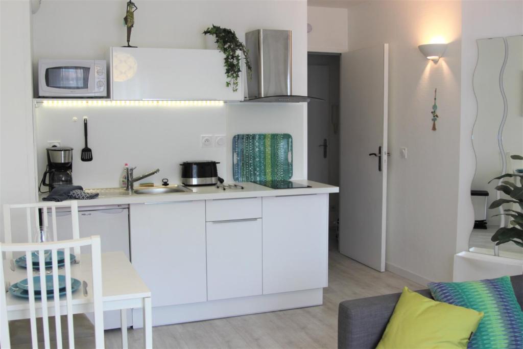 a small kitchen with white cabinets and a couch at Clos Chantegrive in Saint-Médard-en-Jalles