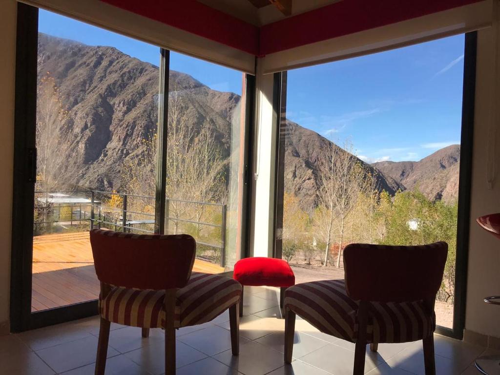 een kamer met 2 stoelen en een groot raam met uitzicht op de bergen bij Cabaña en Barrio Privado de Potrerillos in Potrerillos