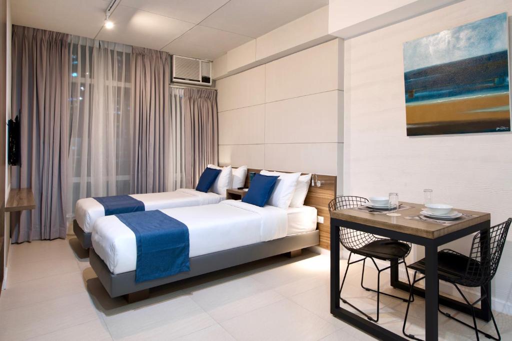 a hotel room with two beds and a table at The Sphere Serviced Residences Managed by HII in Manila