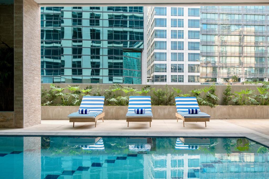 two lounge chairs next to a swimming pool at The Sphere Serviced Residences Managed by HII in Manila