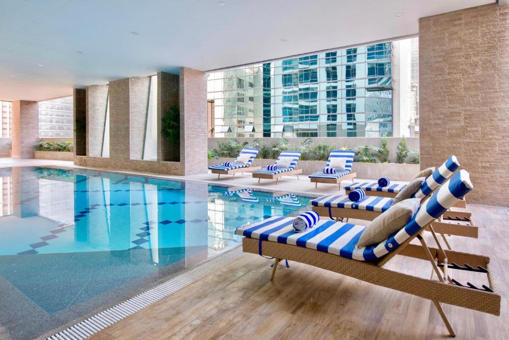 a swimming pool with lounge chairs and a large building at The Sphere Serviced Residences Managed by HII in Manila