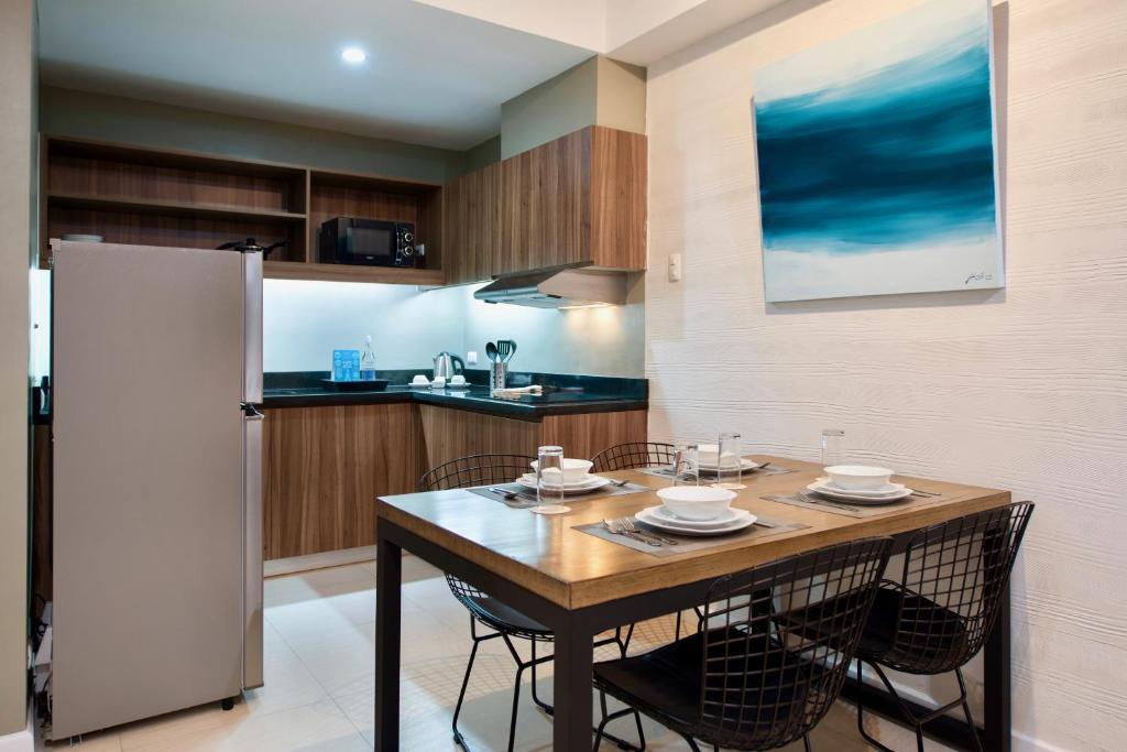 a kitchen with a table with chairs and a refrigerator at The Sphere Serviced Residences Managed by HII in Manila
