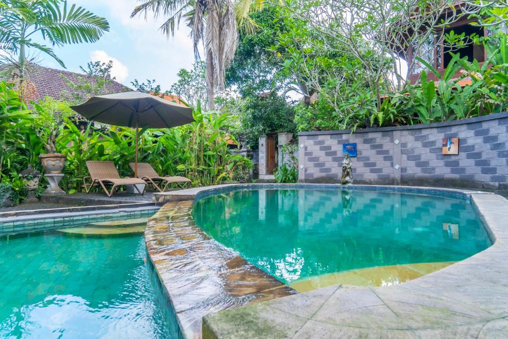 a swimming pool in a yard with an umbrella at Sari Bamboo Bungalows in Ubud