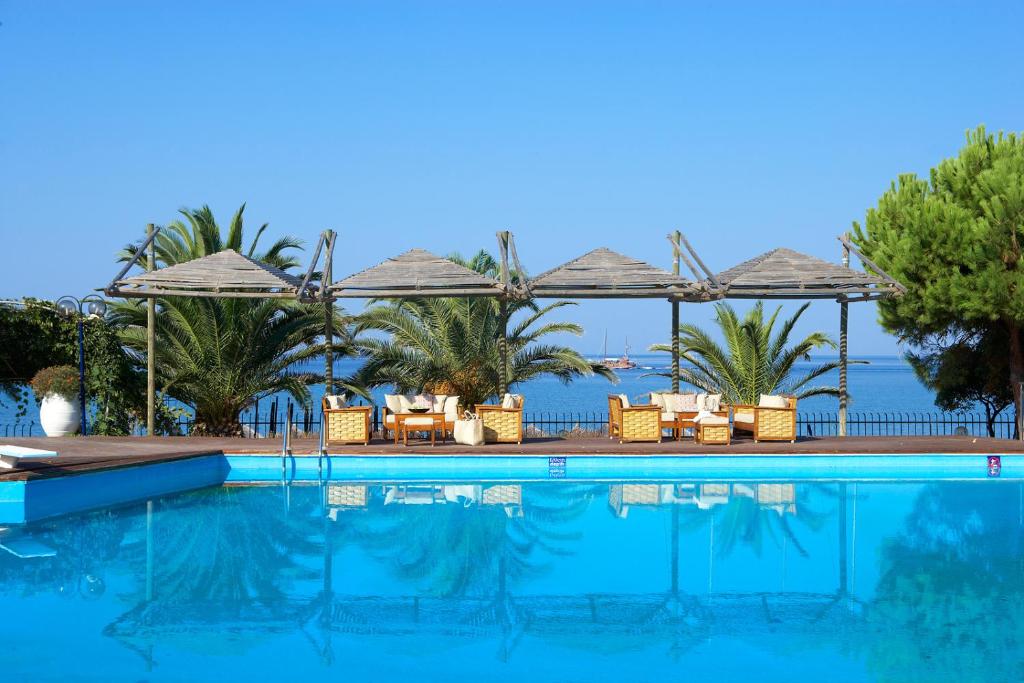 a swimming pool with chairs and umbrellas at Kamari Beach Hotel in Potos