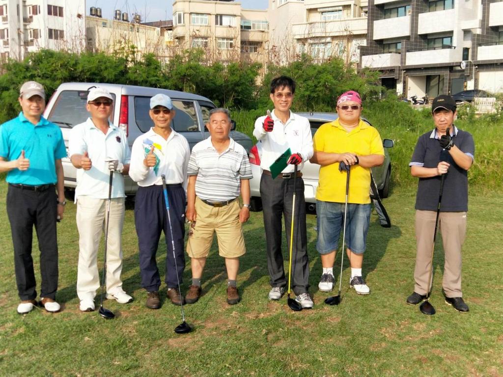 a group of people posing for a picture with golf clubs at We home in Magong