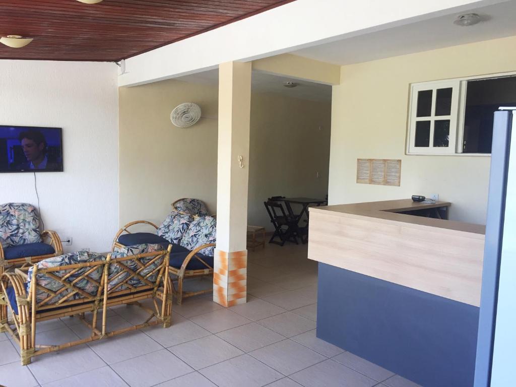 a kitchen and living room with chairs and a counter at Hospedagem Caravela in Arraial do Cabo