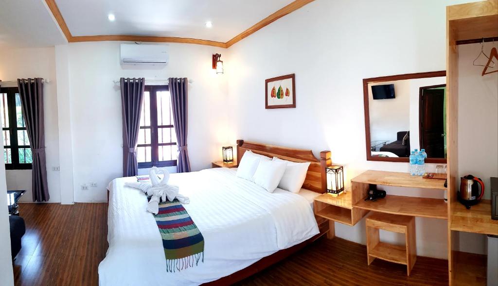 a bedroom with a bed and a desk and a mirror at Liberty Place in Luang Prabang