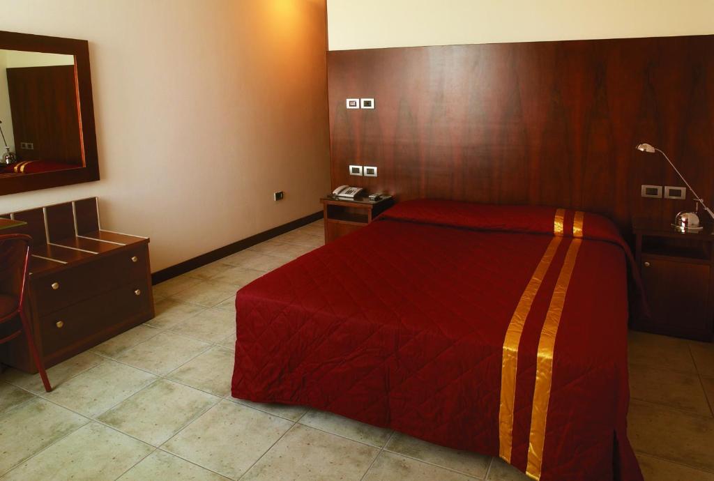 a bedroom with a red bed and a mirror at La Corte Albergo Meublé in Bagnolo San Vito