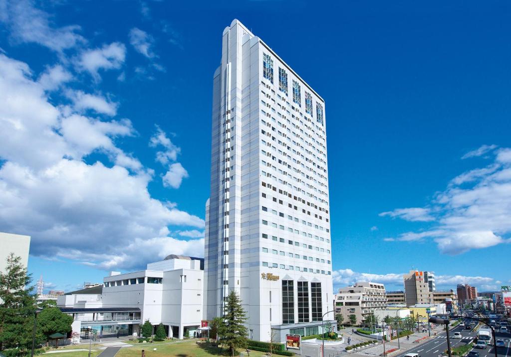 een hoog wit gebouw in een stad met een blauwe lucht bij Miyako Hotel Amagasaki in Amagasaki