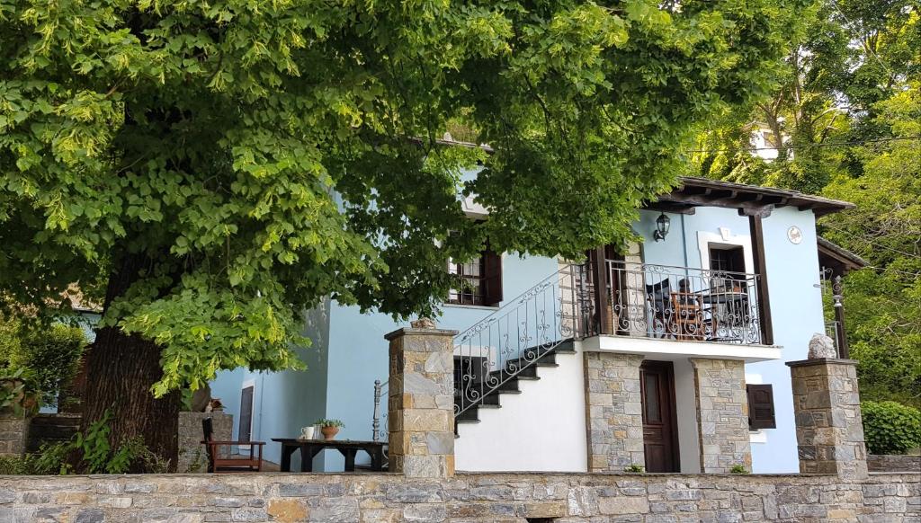 ein Haus mit einem Balkon und einem Baum in der Unterkunft Tsagarada Stone House 1898 in Tsagkarada