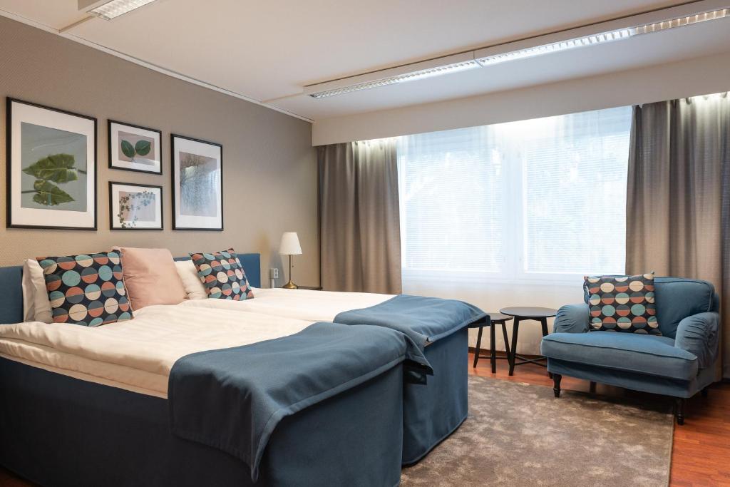 a bedroom with a large bed and a blue chair at Hotel Sorsanpesä in Seinäjoki