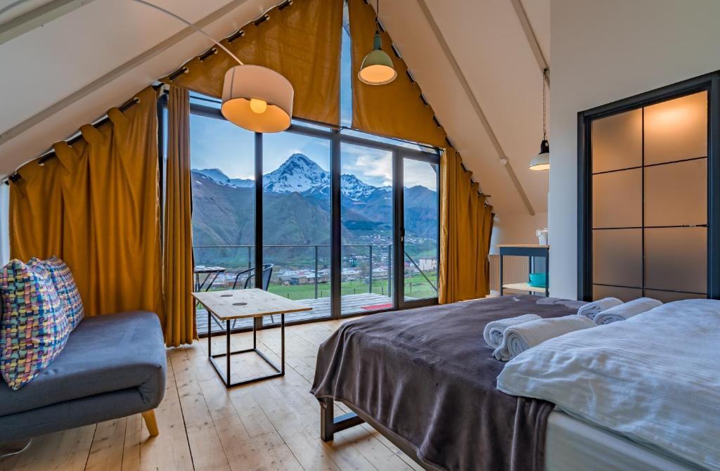 a bedroom with a large window with a mountain view at Kazbegi View in Stepantsminda