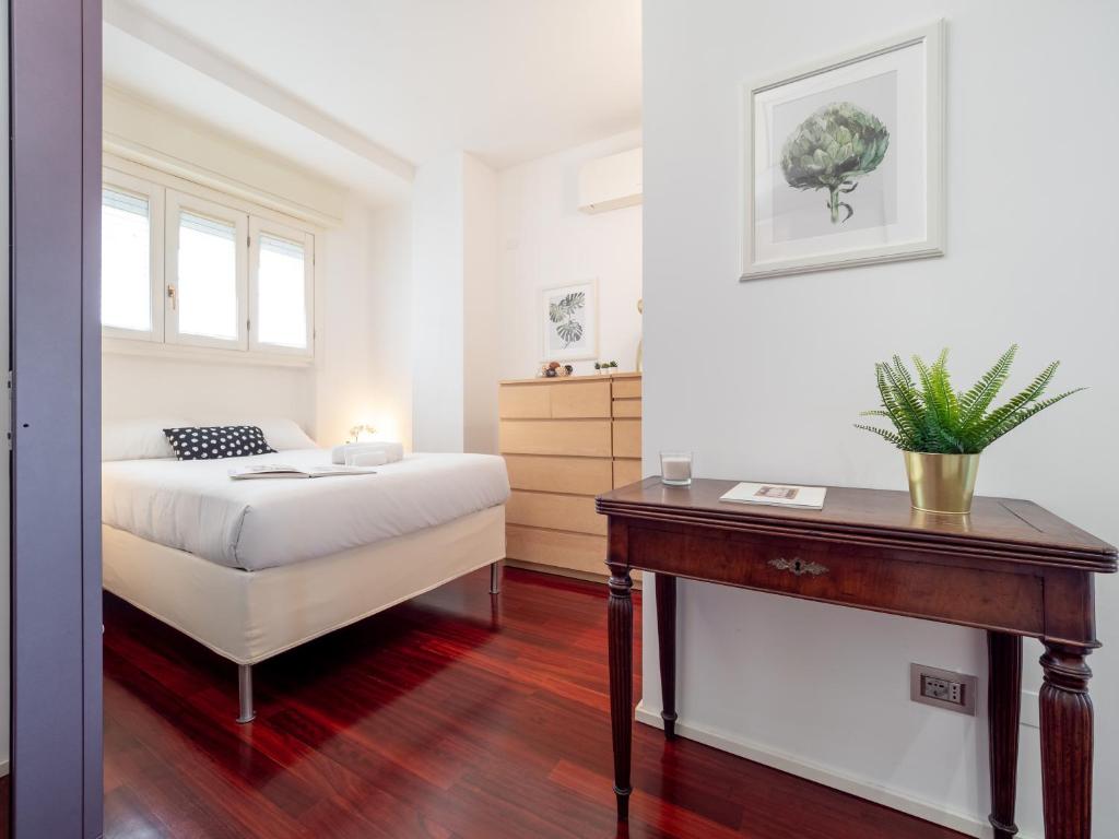 a bedroom with a bed and a table and a dresser at Apartament Vigliani 19 in Milan