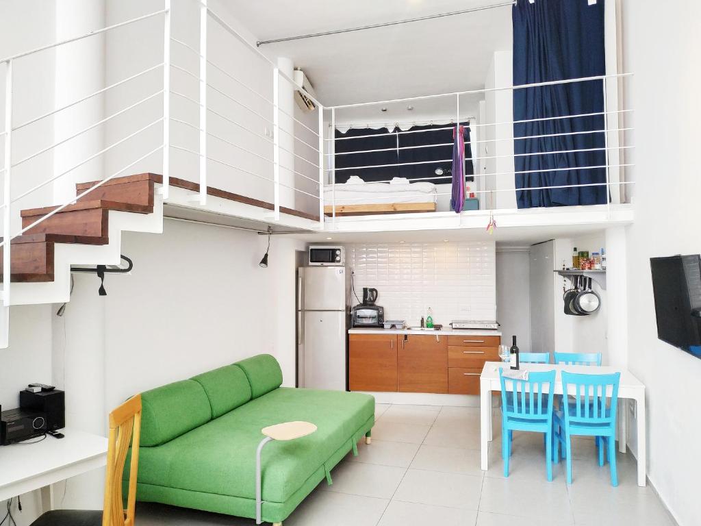 a living room with a green couch and a kitchen at AirTLV - Centrally Located Studio With Gallery in Tel Aviv