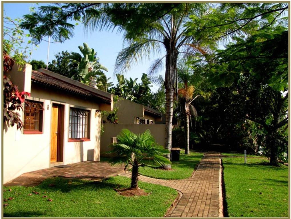 a house with a palm tree next to a sidewalk at Eagles Nest Chalets in Hazyview