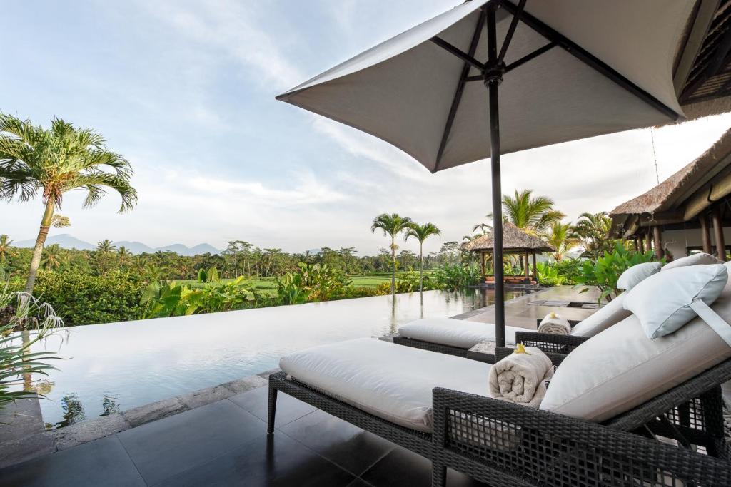 an outdoor patio with an umbrella and a pool at Villa Rumah Lotus in Payangan
