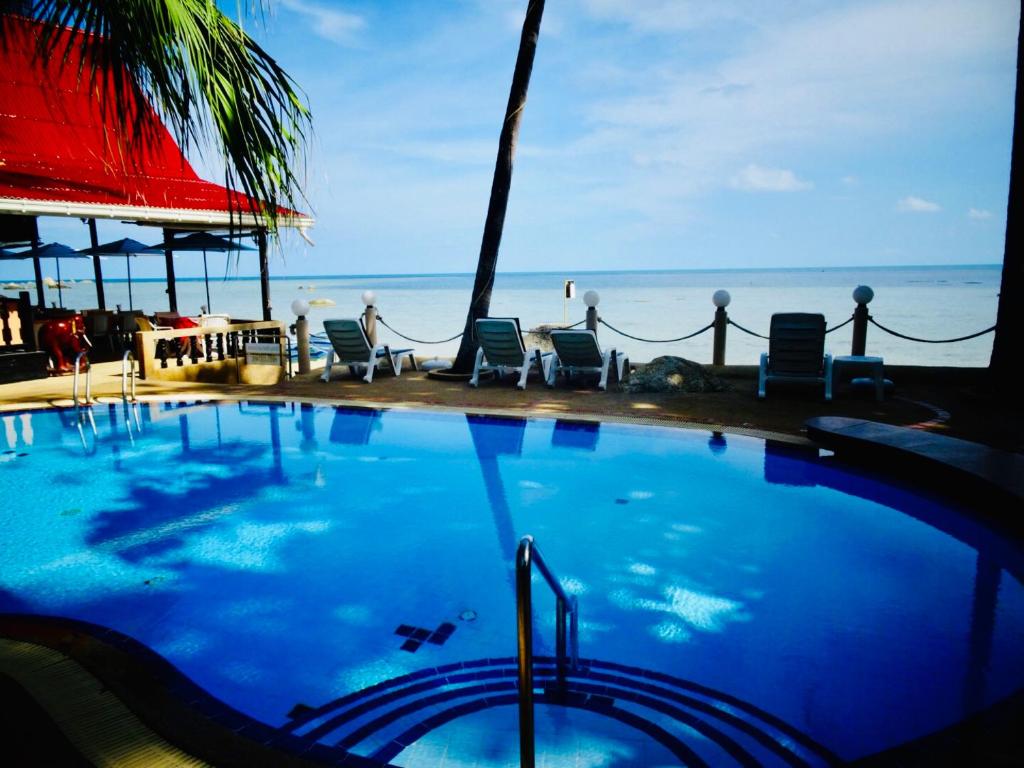 a swimming pool with chairs and the ocean in the background at Starbay Samui in Koh Samui 