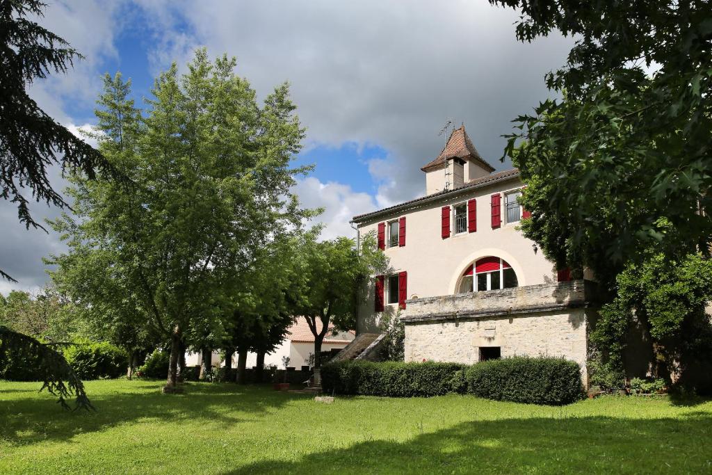 ein altes Haus mit roten Rollläden auf einem grünen Hof in der Unterkunft EARL DOMAINES DELMAS in Parnac