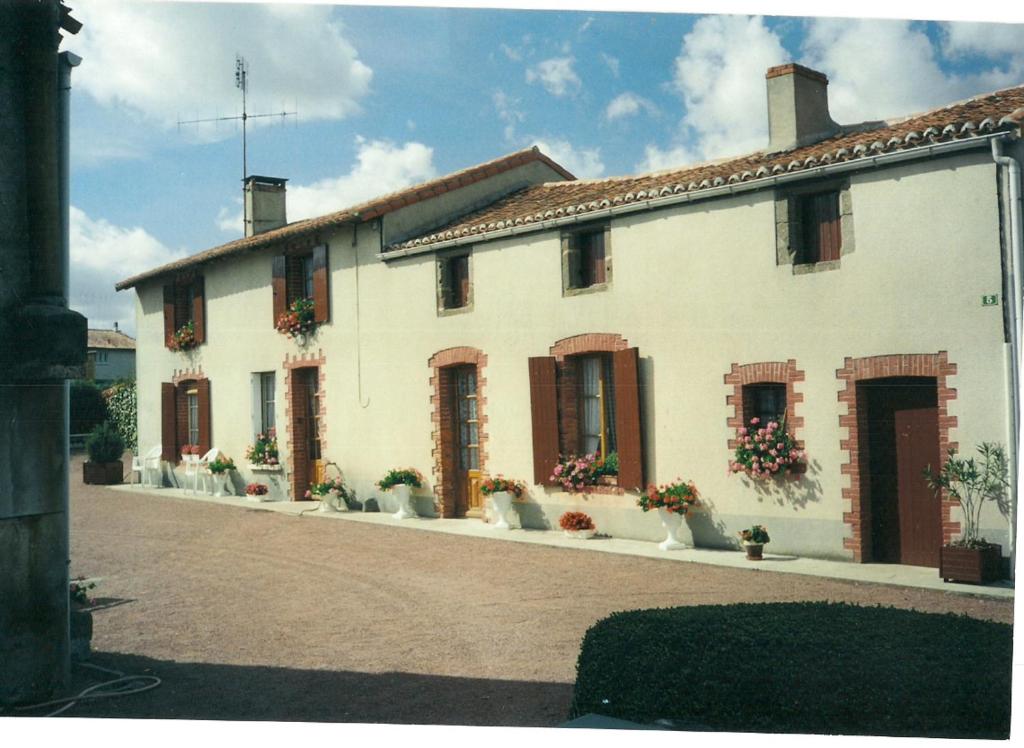 une grande maison blanche avec des pots de fleurs devant elle dans l'établissement No 5, à Moutiers-sous-Argenton