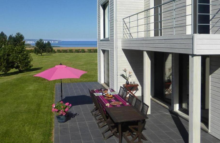 una mesa con una sombrilla rosa en el patio en villa les falaises, en Berneval-le-Grand