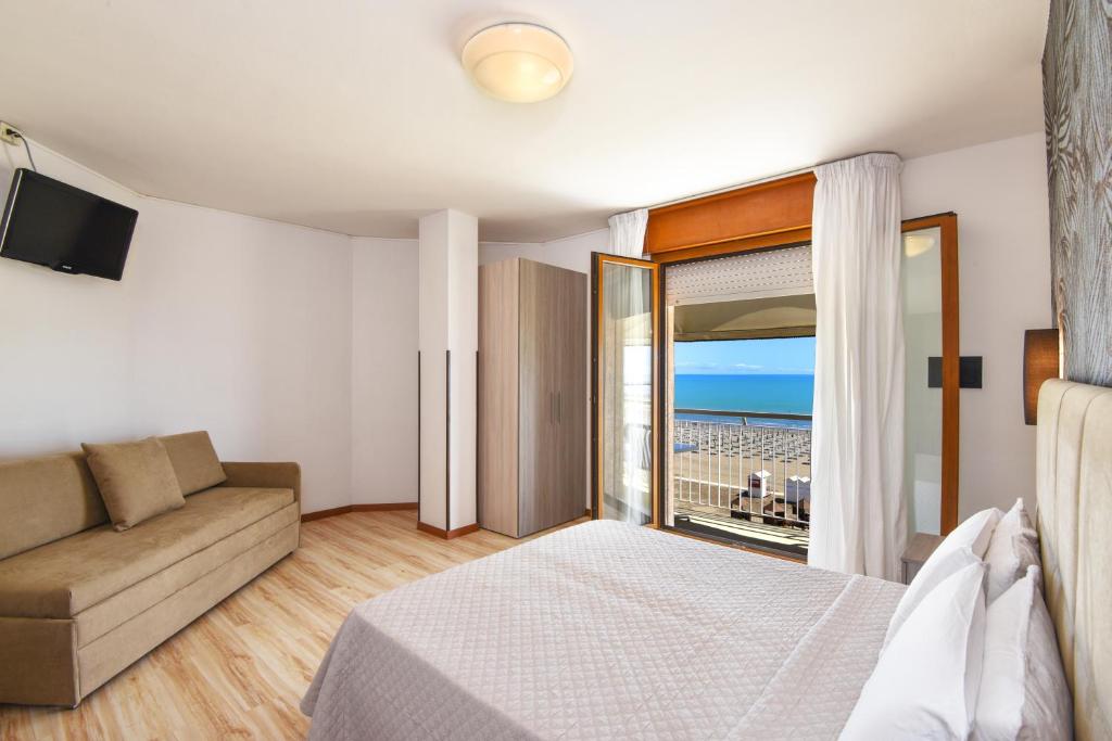 a bedroom with a bed and a couch and a balcony at Hotel Excelsior in Caorle