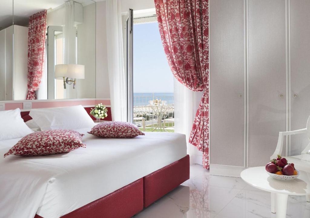 a bedroom with a large bed and a large window at Hotel Milton Rimini in Rimini