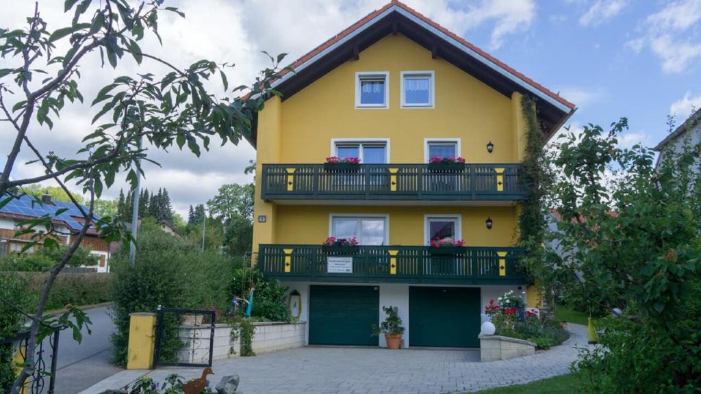 una casa amarilla con un balcón con flores. en Ferienwohnung Bucher Ursula, en Waldmünchen