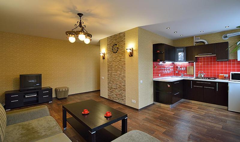 ein Wohnzimmer mit einem Sofa und einem Tisch sowie eine Küche in der Unterkunft Квартира на пр. Яворницкого in Dnipro