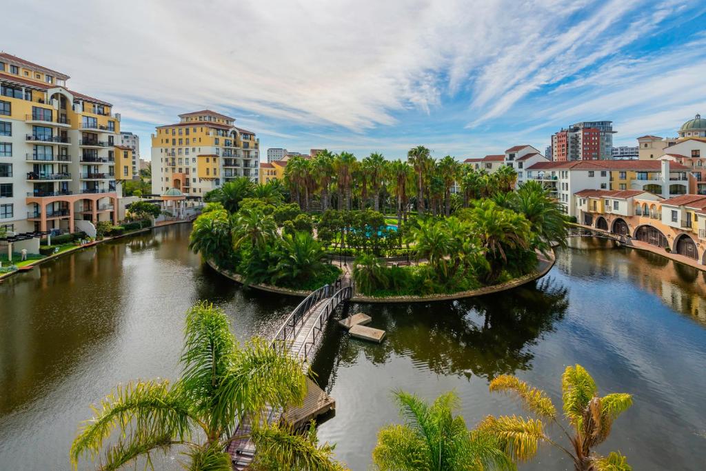 a river in a city with palm trees and buildings at Majorca Self-Catering Apartments in Cape Town