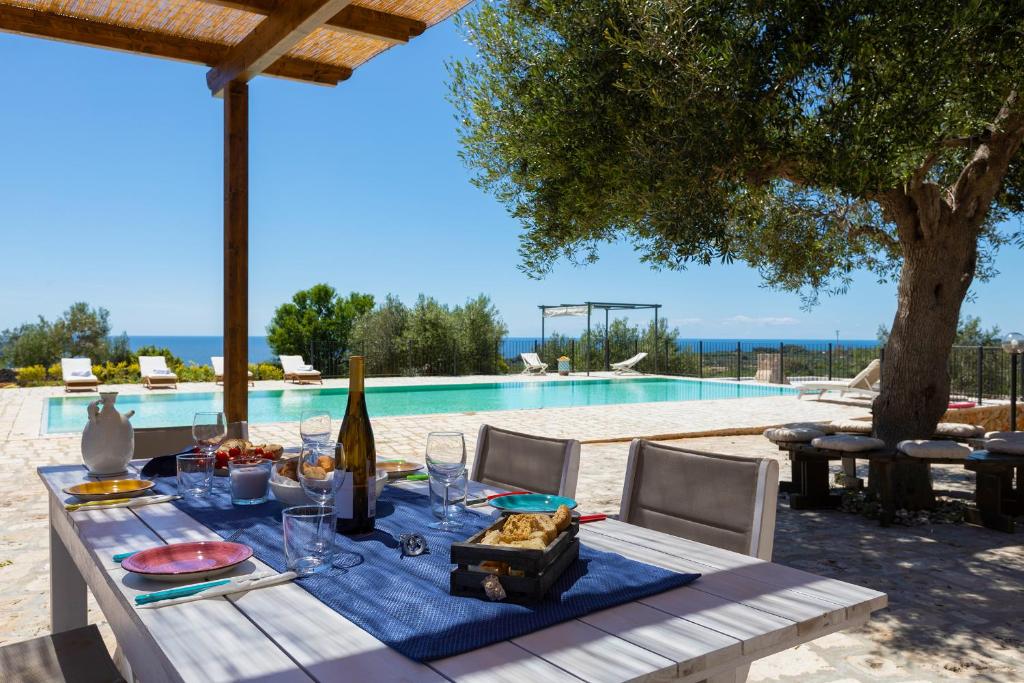 een tafel met een fles wijn en wijnglazen naast een zwembad bij Tenuta Regina in Castrignano del Capo