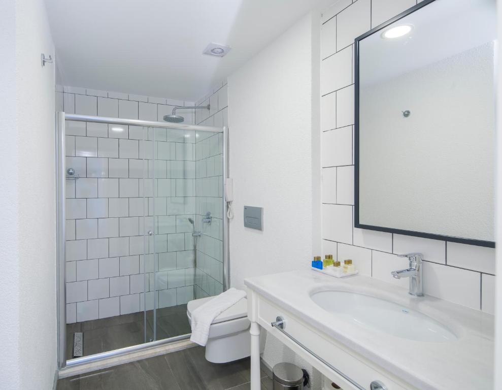 a white bathroom with a sink and a shower at La Kumsal Hotel in Kaş