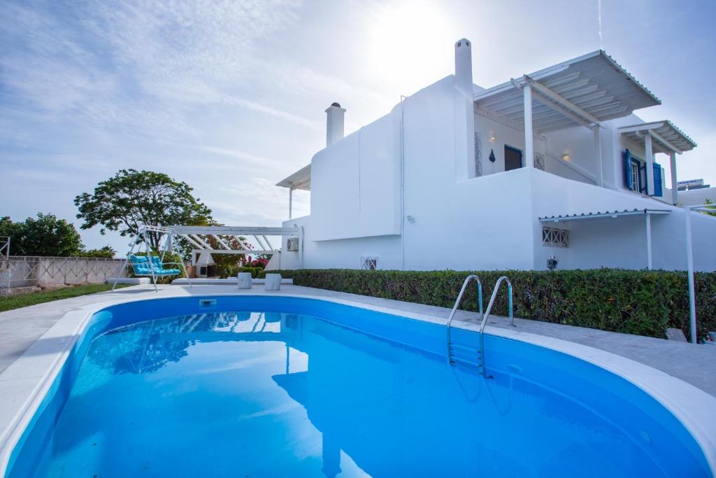 a villa with a swimming pool in front of a house at Sarwnisland in Lagonissi