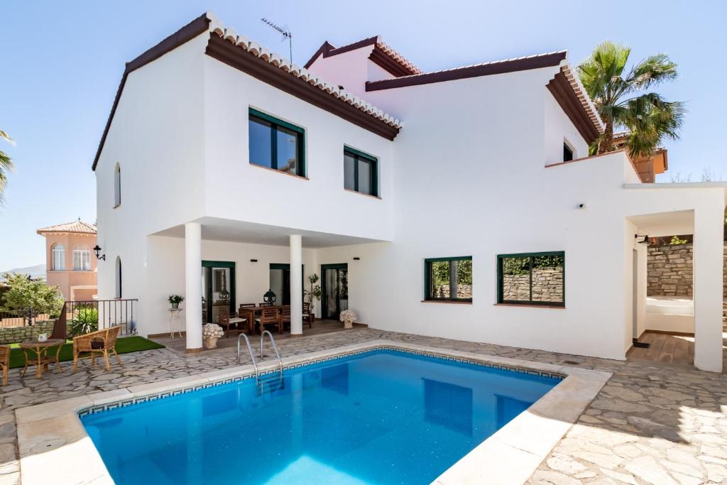 a villa with a swimming pool in front of a house at Villa La Piedad in Otura