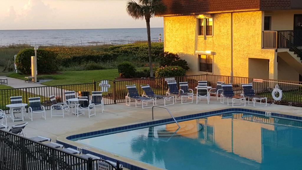 a swimming pool with chairs and a building and the ocean at Beautiful Ocean view Townhouse in Cocoa Beach
