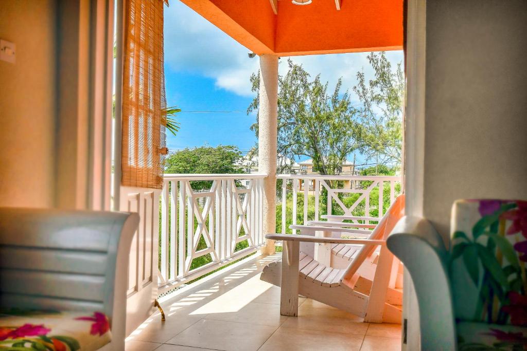 a balcony with an orange umbrella and a table and chairs at Best E Villas Providence in Christ Church